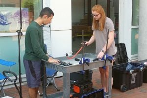 two college students test equipment as part of sound propagation research.