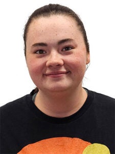 young white woman in black tee shirt with dark brown pulled back hair, smiling in front of a white background