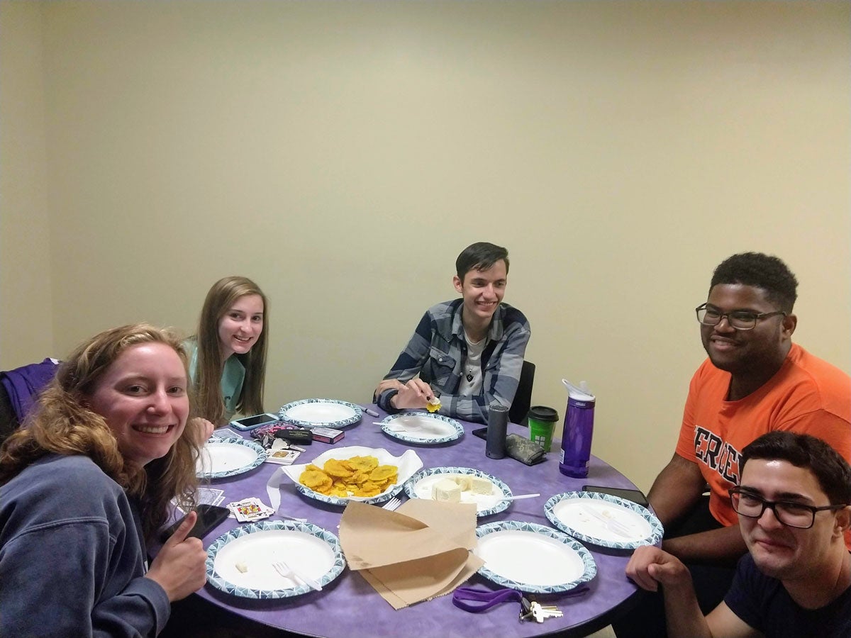 group of students sitting around a small table sharing plates of food