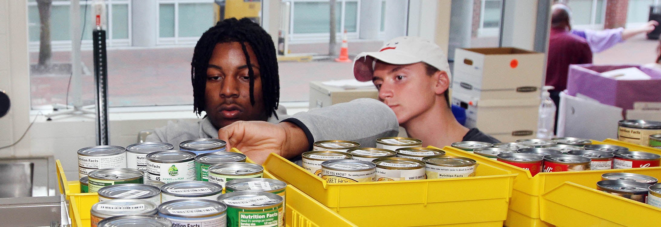 East Carolina University students Myles Berry, left, and Jack Hunike help stack food from the ‘a little heart goes a long way’ food drive Monday, March 2, 2020, in the Industrial Distribution and Logistics  student service learning lab in the Science and Technology Building. (Photo by Ken Buday)