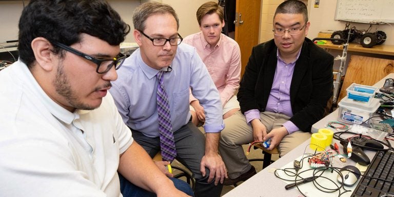 ECU senior Robert Ocampo (left) shows Dr. Dan Dickerson how to retrieve data from the sensors. Also pictured (from left) are freshman Ethan Smith and Dr. Zhen Zhu. (Photos by Rhett Butler) 