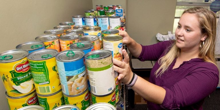 Ashton Fisher stocks the shelves at the Purple Pantry with canned goods. (ECU file photo by Rhett Butler)