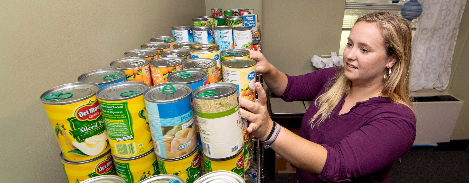 Ashton Fisher stocks the shelves at the Purple Pantry with canned goods. (ECU file photo by Rhett Butler)