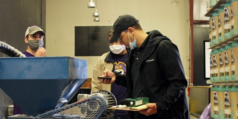 Engineering students Michael Trapani, right, and Kenneth Weddle, along with Dr. Tarek Abdel-Salam, director of the East Carolina University Center for Sustainable Energy and Environmental Engineering, examine equipment during an energy audit at Shortway Brewing. (Photos by Ken Buday)