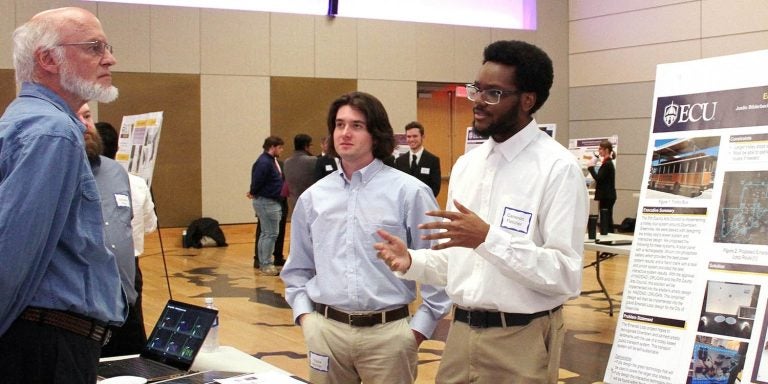 Engineering students Cameron Fletcher, left, and Trippe Bonner, center, discuss improvement to the Emerald Tour Trolley Stop as part of a senior capstone project presentation on Monday at the Main Campus Student Center. (Photos by Ken Buday)
