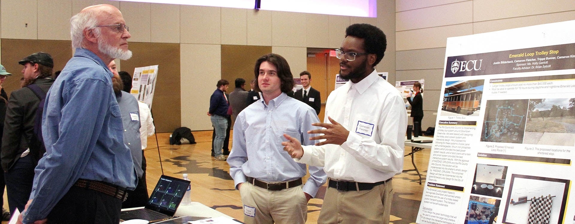 Engineering students Cameron Fletcher, left, and Trippe Bonner, center, discuss improvement to the Emerald Tour Trolley Stop as part of a senior capstone project presentation on Monday at the Main Campus Student Center. (Photos by Ken Buday)
