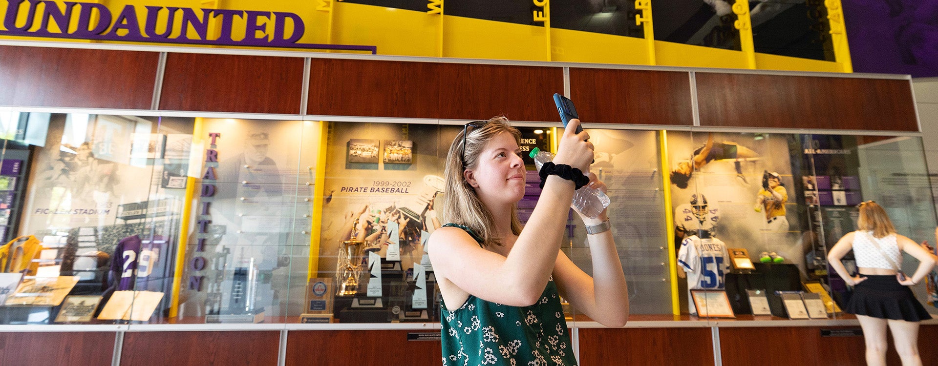 Jarieke de Haas, a student from the Netherlands, takes a video of the Hall of Fame display cases at Minges Coliseum. (Photo by Rhett Butler)