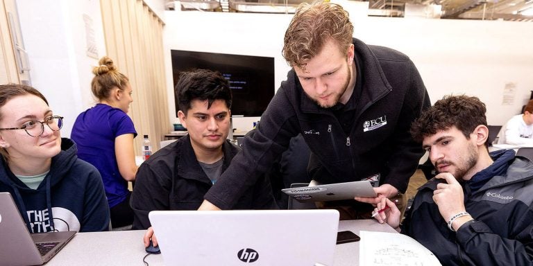 Engineering student Colin Foley, center, works  as a teacher's assistant in an introductory engineering class. Foley, a sophomore, interned with Richard Childress Racing, one of NASCAR's most successful teams. (Photo by Rhett Butler)