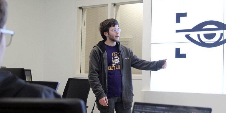ECU senior Collin Roach, head of the student collegiate cyber defense competition club, gives a presentation to students in the Cybersecurity Analysis and Action Center in Science and Technology Building. The National Security Agency recently redesignated ECU as a National Center of Academic Excellence in Cyber Defense (NCAE-CD), a designation the university has held since 2005. (Photos by Ken Buday)