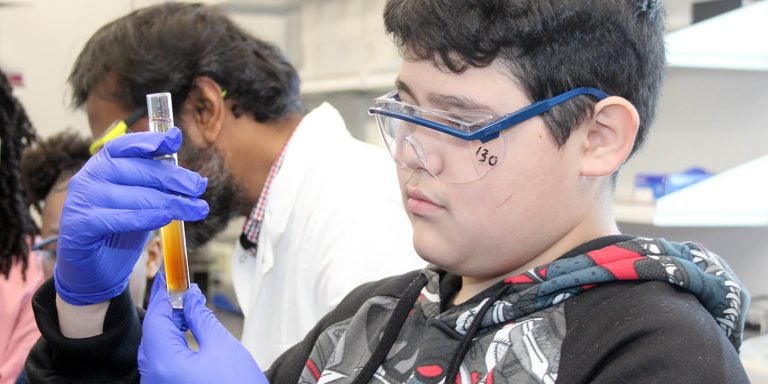 Seventh grader Jason Henderson looks at a test tube of separated coffee as part of a chromotography experiment during a Grow Local tour of the Eastern Region Pharma Center bioprocess engineering labs in the Life Sciences and Biotechnology Building. (Photos by Ken Buday)