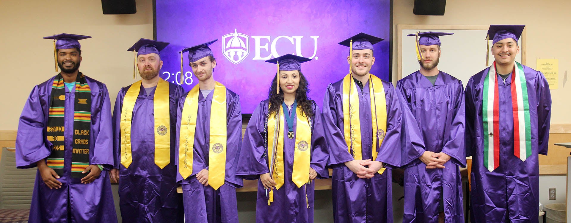 ECU software engineering graduates, from left, Isaiah Wells, James Kinlaw, Ryon Gerringer, Maria Alexandra Ortiz, Alexander Baldauff, Jonathan Jones and Brandon Miranda pose for a picture inside their capstone classroom in the Bate Building. They are the first class of graduates in the Department of Computer Science's Bachelor of Science in software engineering program. (Photos by Ken Buday)